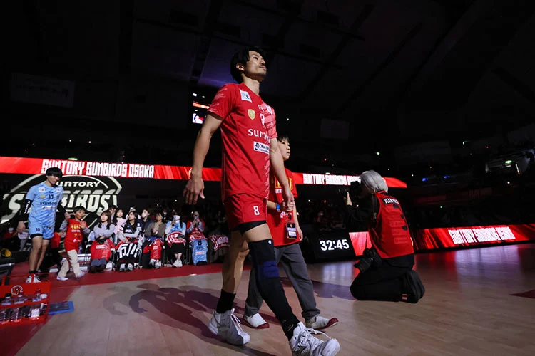 照明を落としたアリーナへ赤いユニホームのサントリー選手が入場する場面