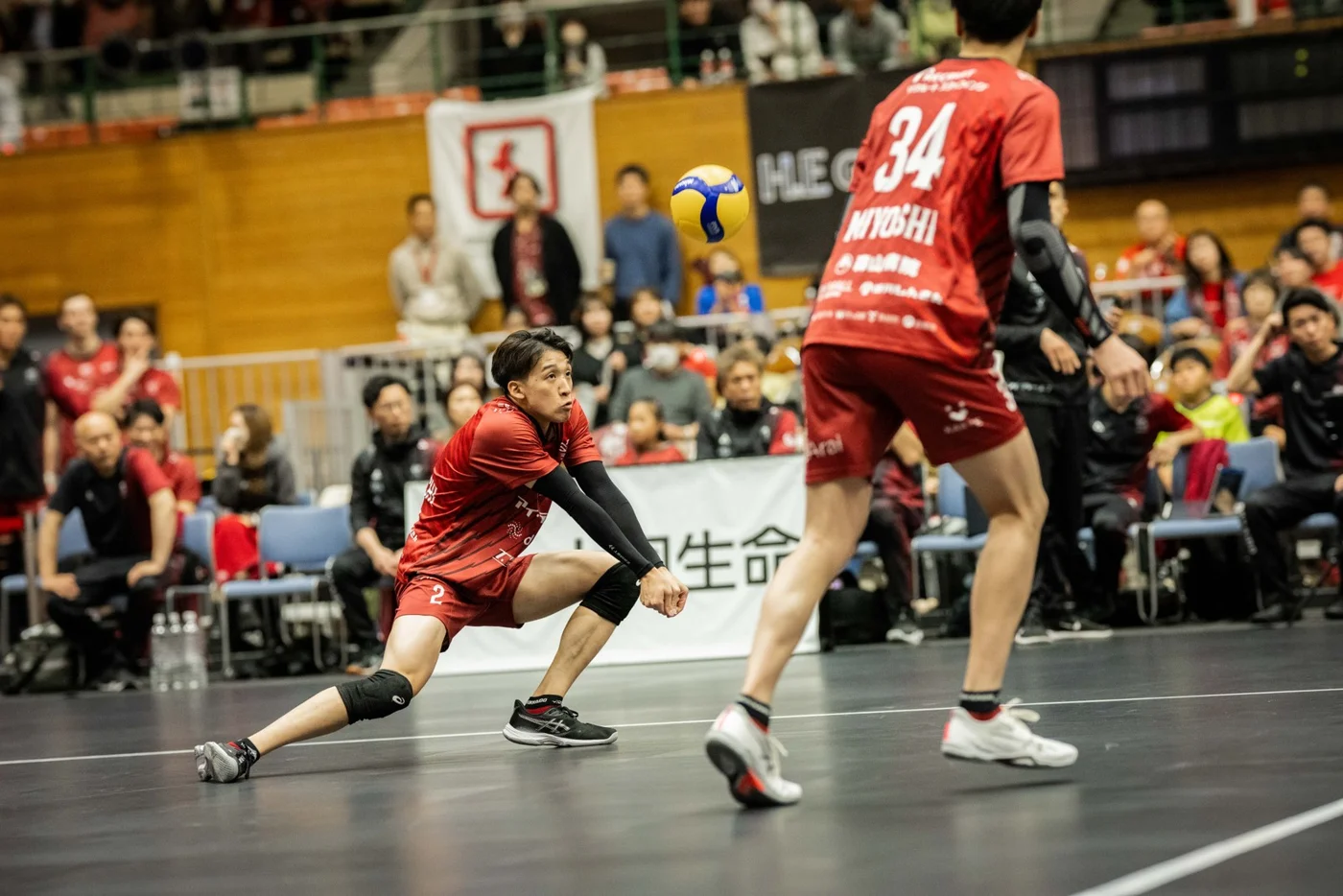 赤いユニフォームのヴォレアス北海道の選手が低い姿勢でボールを受ける場面